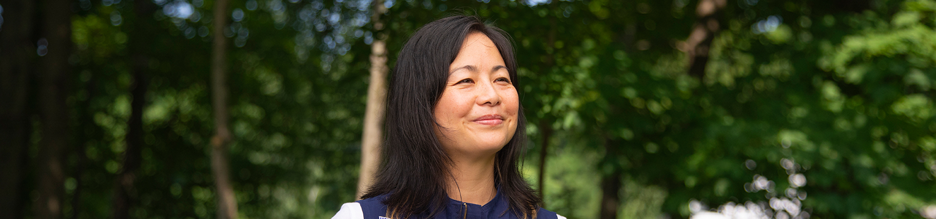  girl scout staff or volunteer wearing adult vest in woods smiling 