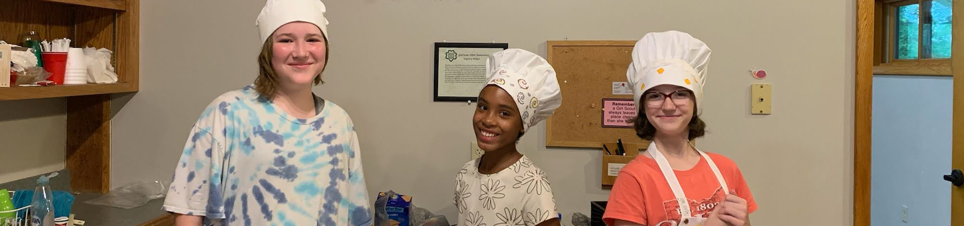  Three girls in chef's hats smiling 