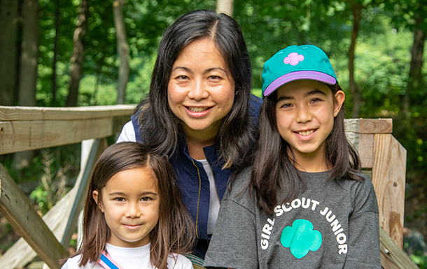 adult volunteer and two girl scouts smiling