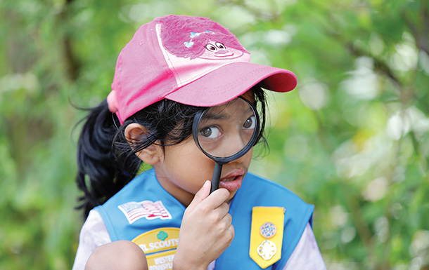 daisy girl scout looking through a magnifying glass